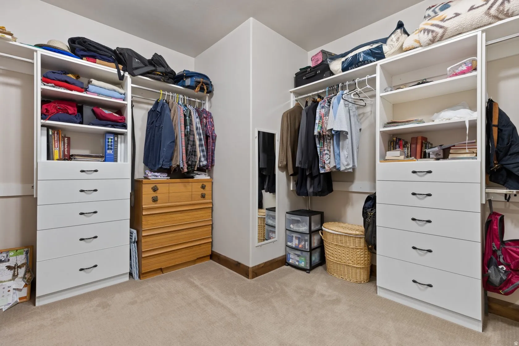 Integrated closet system featuring white built-in shelving, hanging rods, and multiple drawers with dark hardware