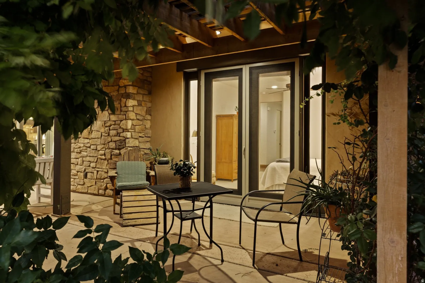 Expansive patio featuring a stone veneer exterior, wood pergola, and sliding glass doors