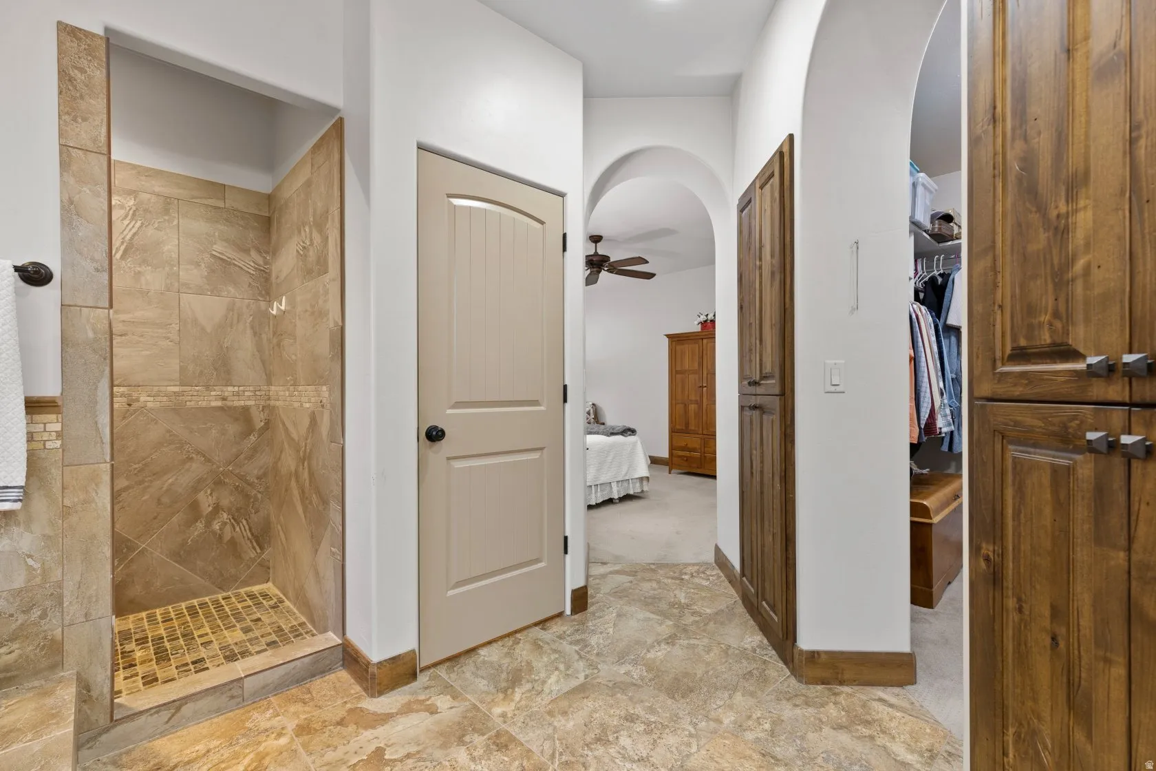 Walk-in shower with natural stone-look tile, mosaic tile accent, and mosaic tile pan