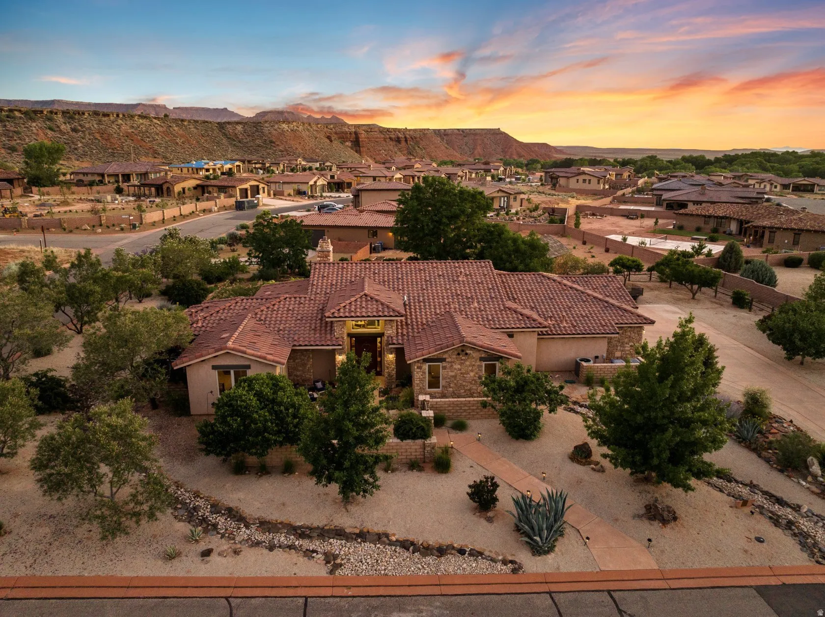 Desert landscape property featuring a tile roof, stone and stucco exterior, and an integrated garage