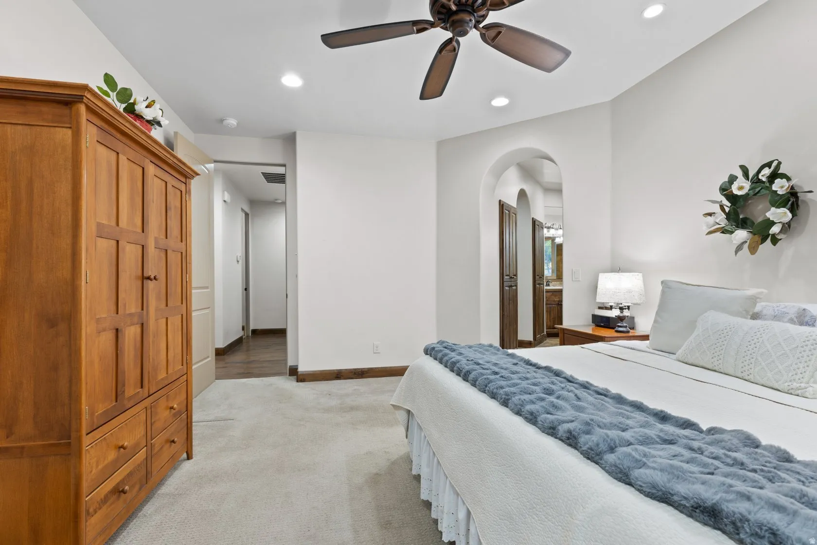 Carpeted flooring extending throughout, leading to an arched doorway