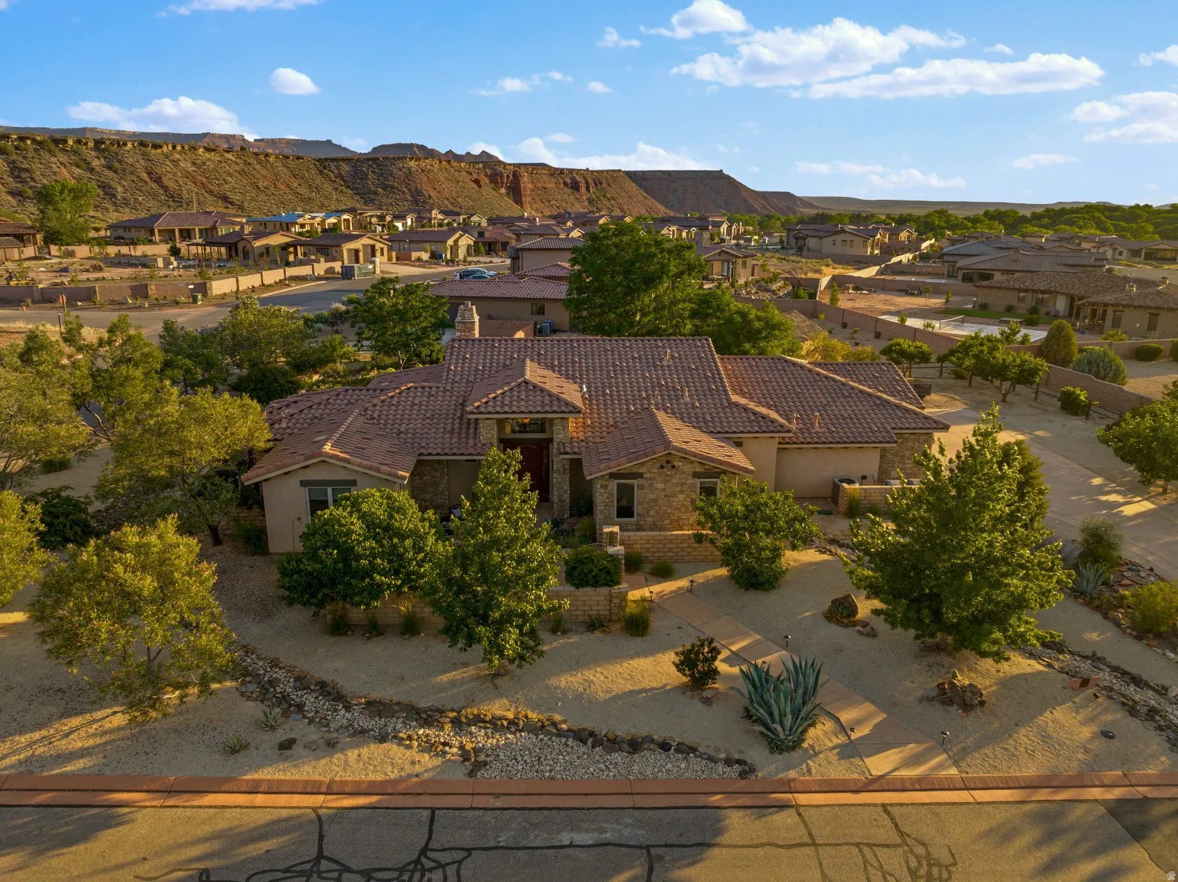 Southwestern-style residence featuring a tile roof, stucco exterior, and stone accents