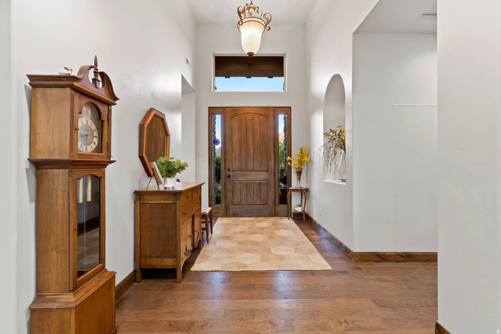 Grand entryway featuring a solid wood door with sidelights, transom window, and a decorative overhead light fixture