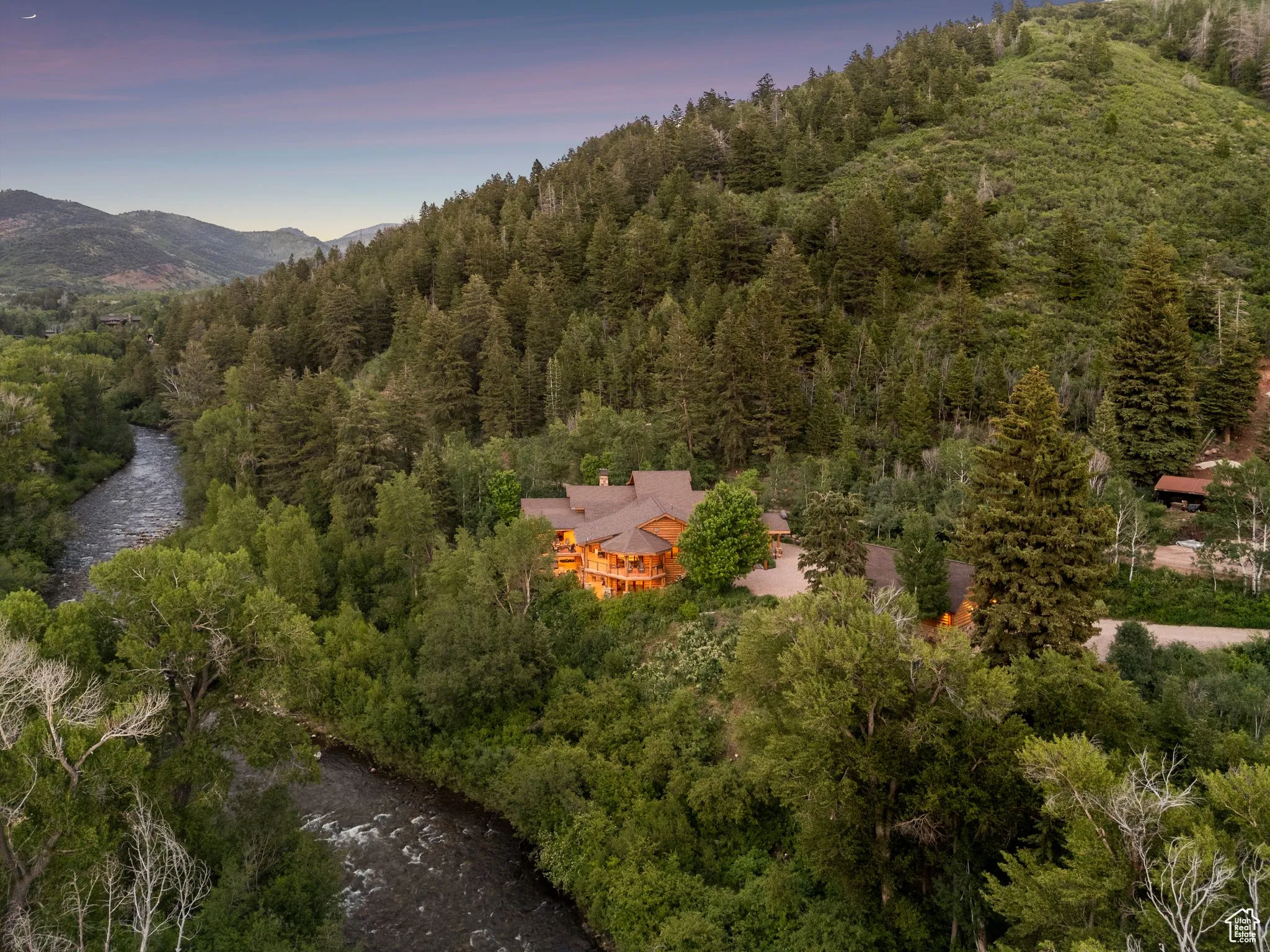 Aerial view of property and surrounding area featuring a heavily wooded area and mountains
