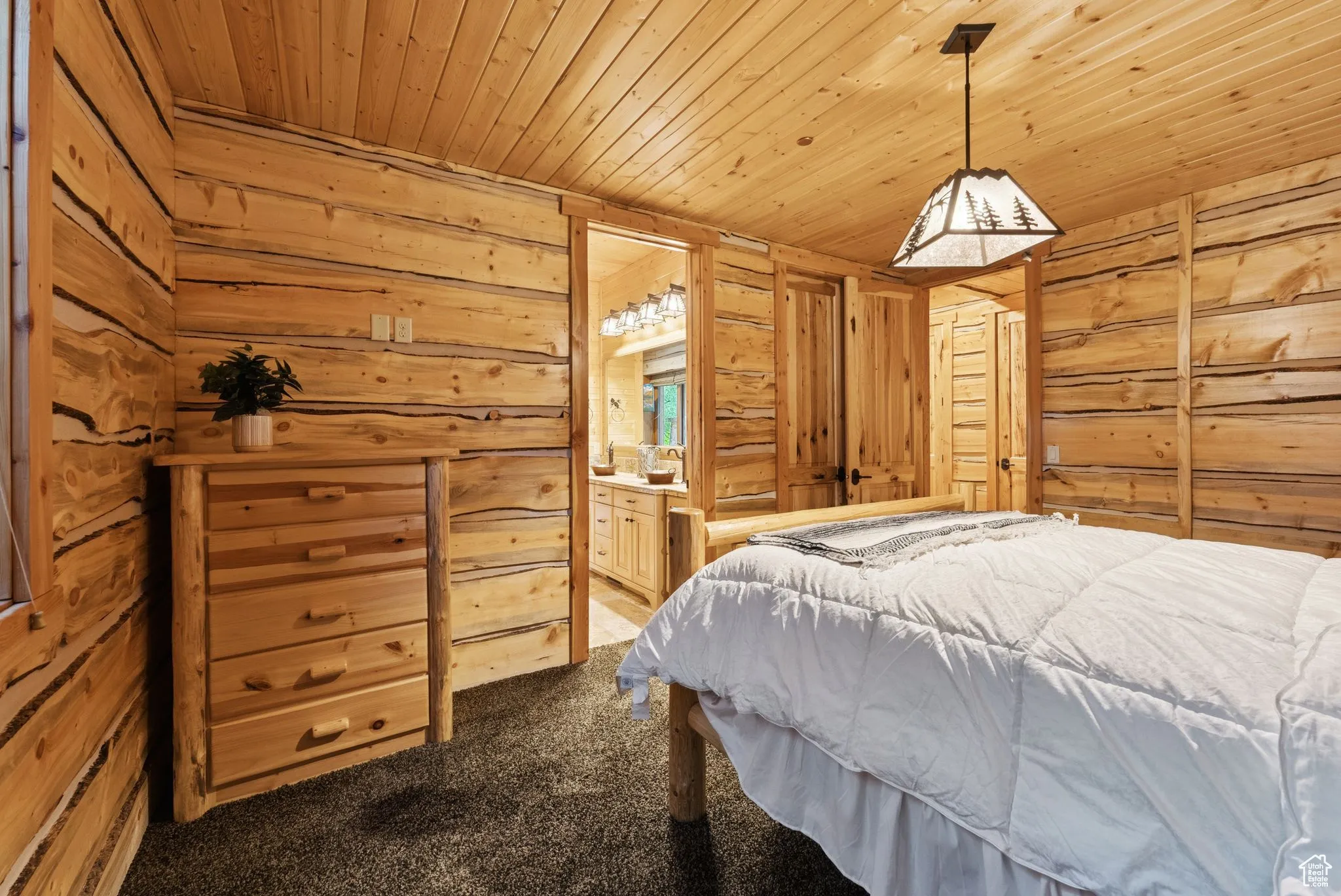 Bedroom with carpet floors, tongue-in-groove ceiling, split log walls, and connected bathroom