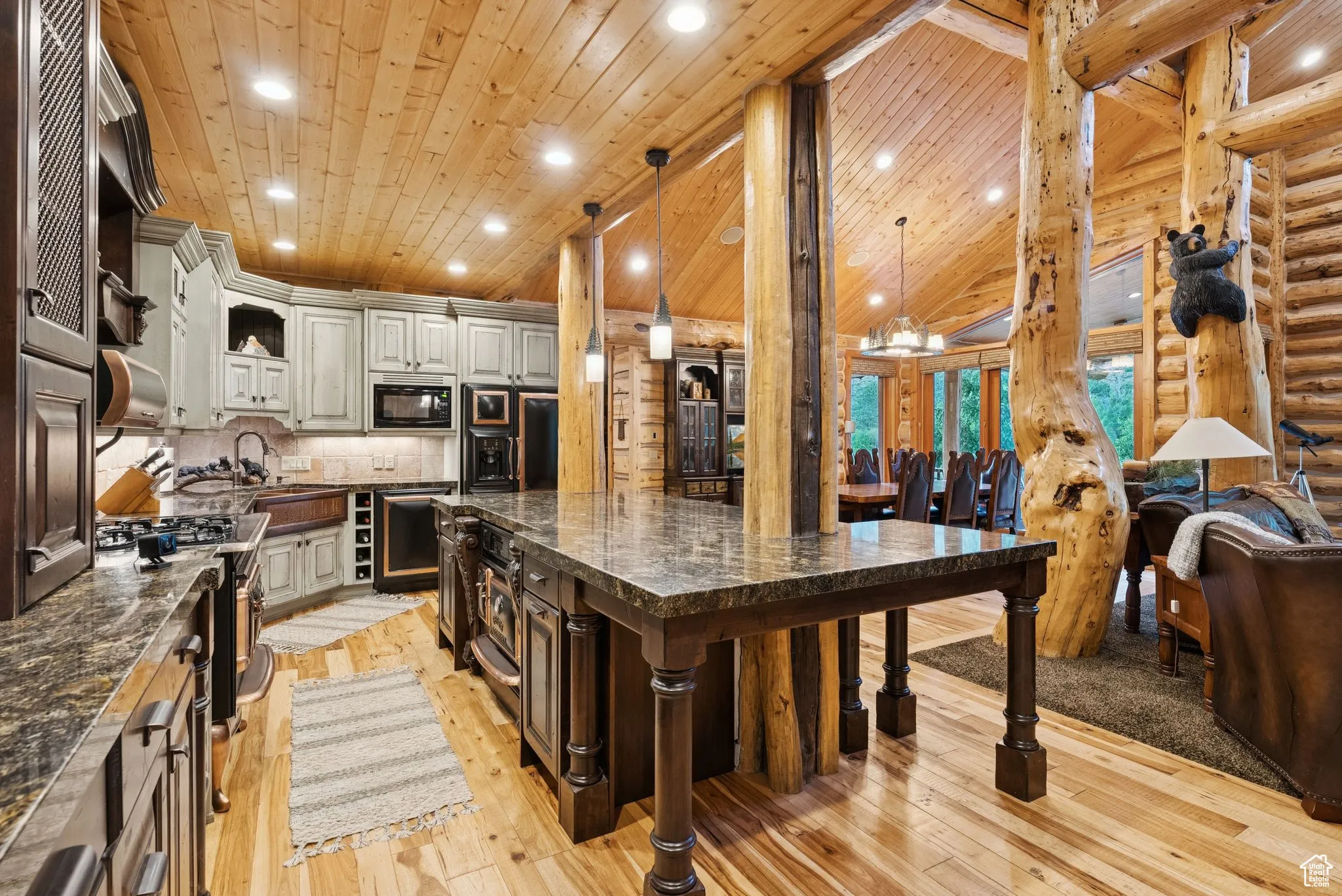 Kitchen with black microwave, refrigerator, light wood flooring, a kitchen bar, and a large island