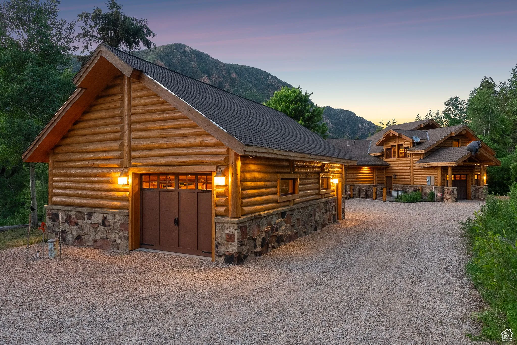 split-log veneer, framed home with stone siding, log exterior, a mountain view, roof with shingles, and driveway