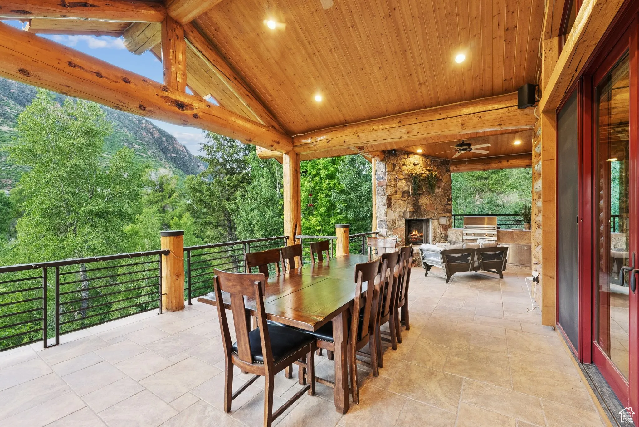 View of patio with outdoor dining area, an outdoor stone fireplace, and a ceiling fan