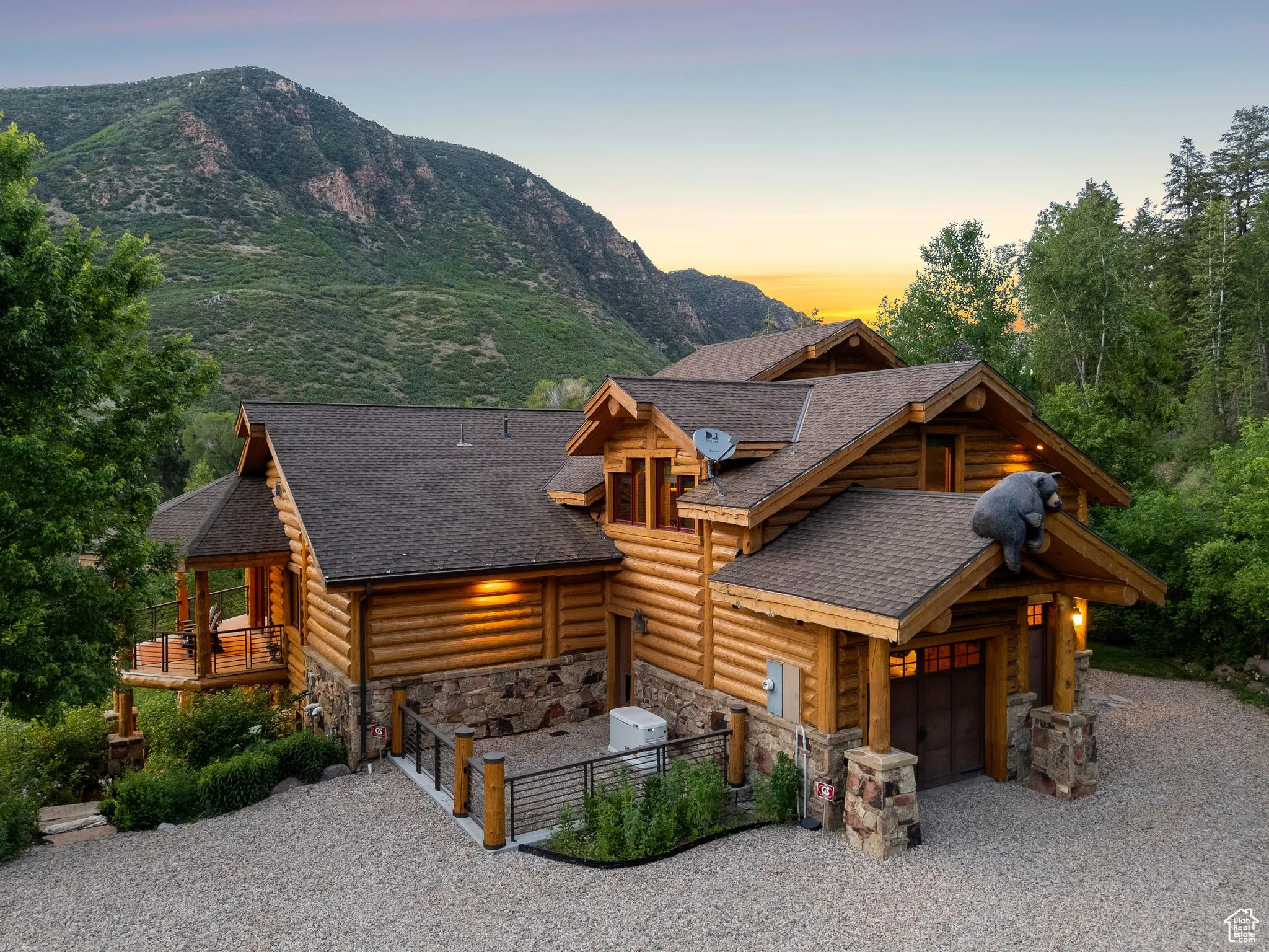 Split-log veneer, framed home with driveway, stone siding, a garage, a shingled roof, and a mountain view