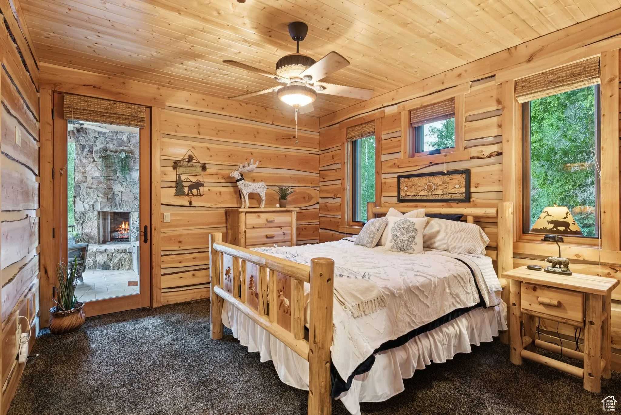 Bedroom with tongue-in-groove ceiling, dark colored carpet, access to outside, wooden walls, and a fireplace