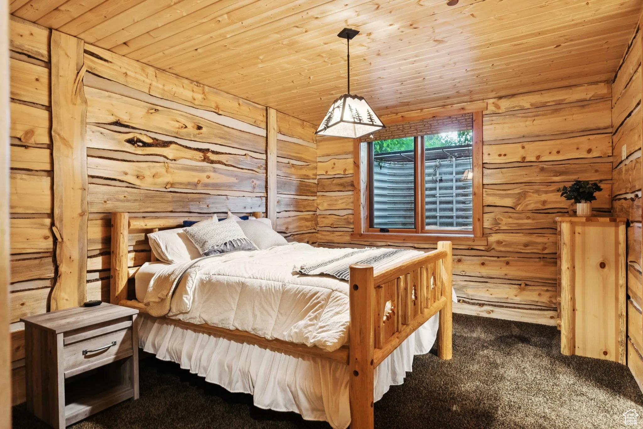 Carpeted bedroom with split log walls and tongue-in-groove ceiling