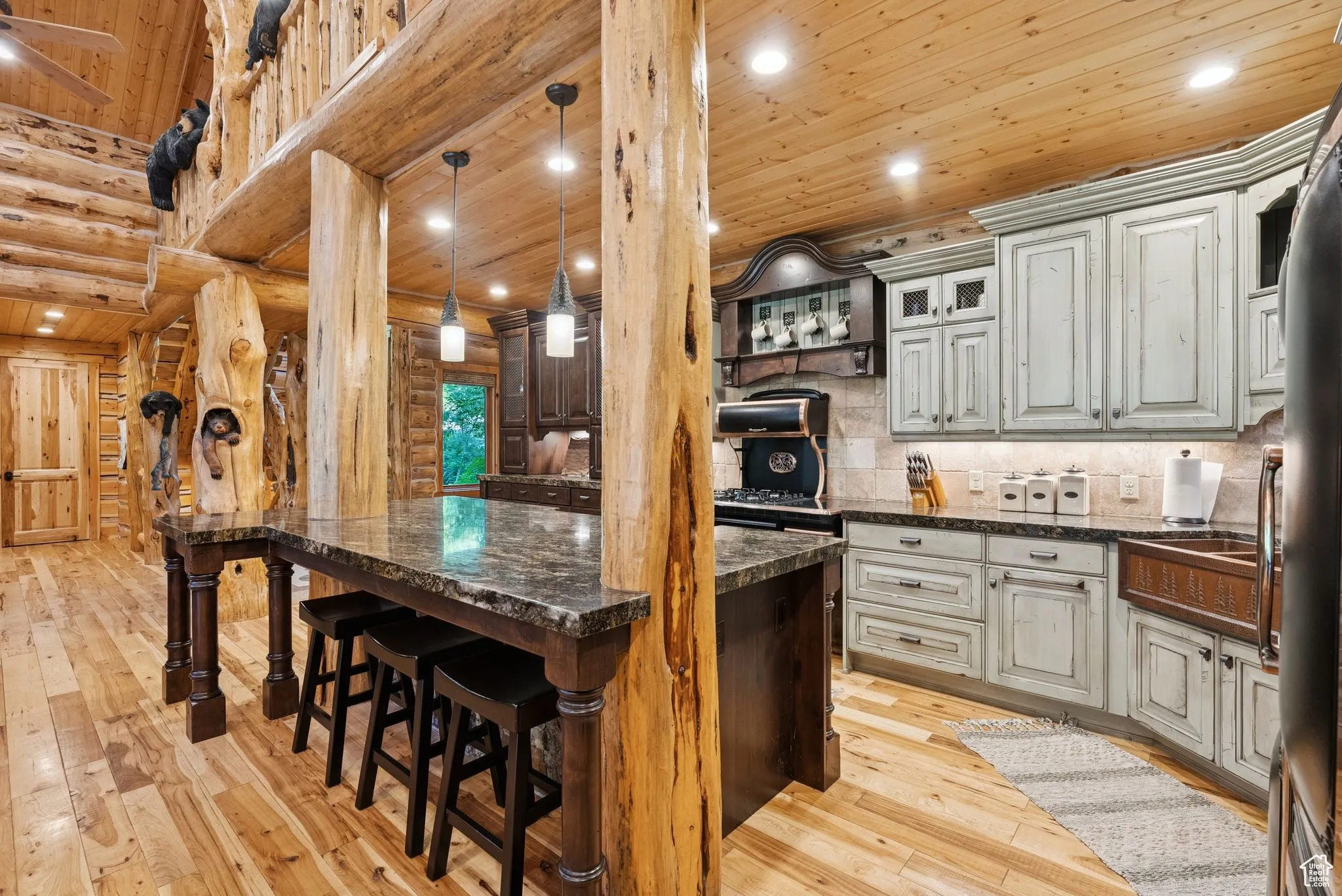 Kitchen with split-log walls, tongue-in-groove ceiling, light wood floors, a breakfast bar area, and a kitchen island