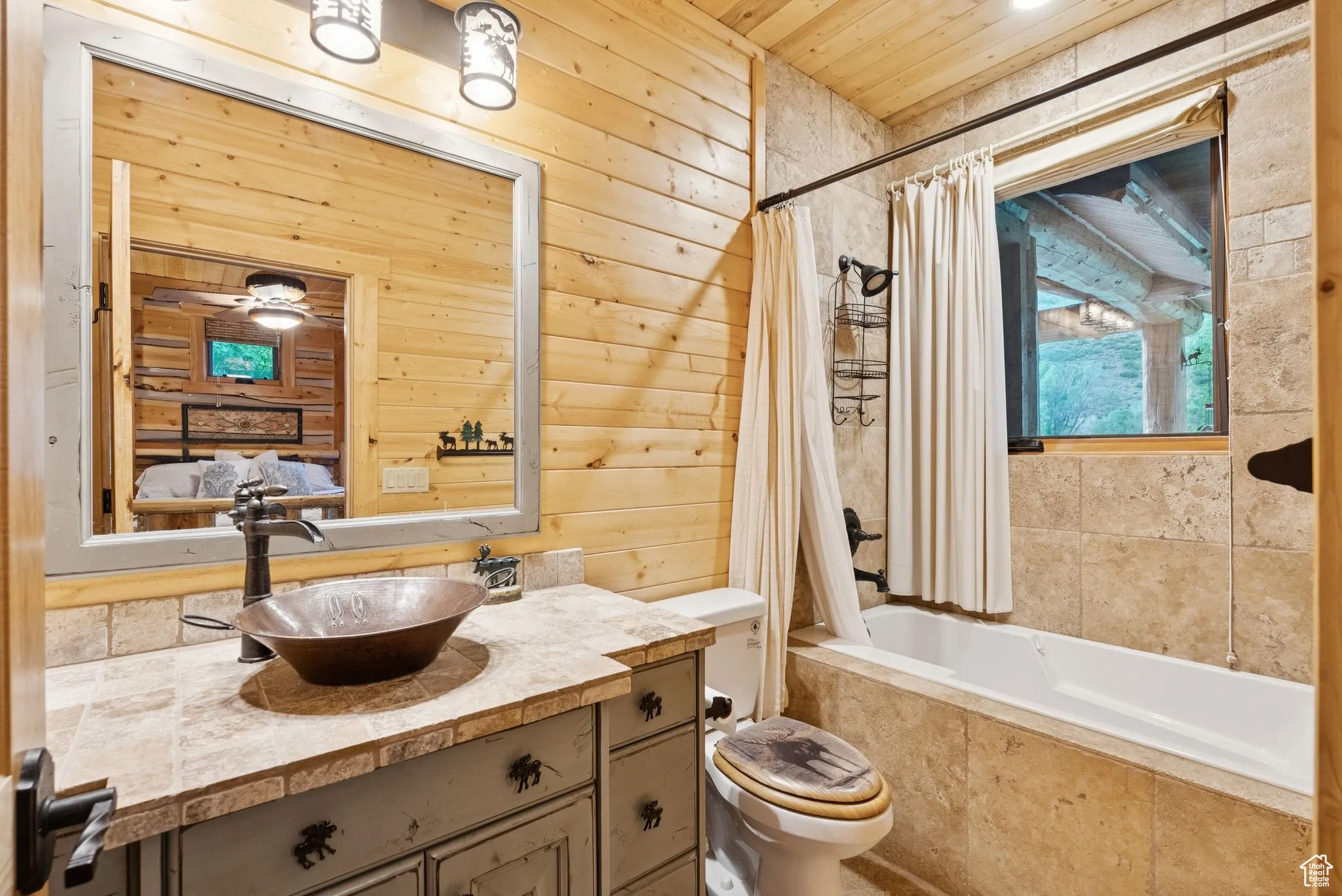 Full bathroom featuring wood walls, vanity, tiled shower / bath combo, and tongue-in-groove ceiling