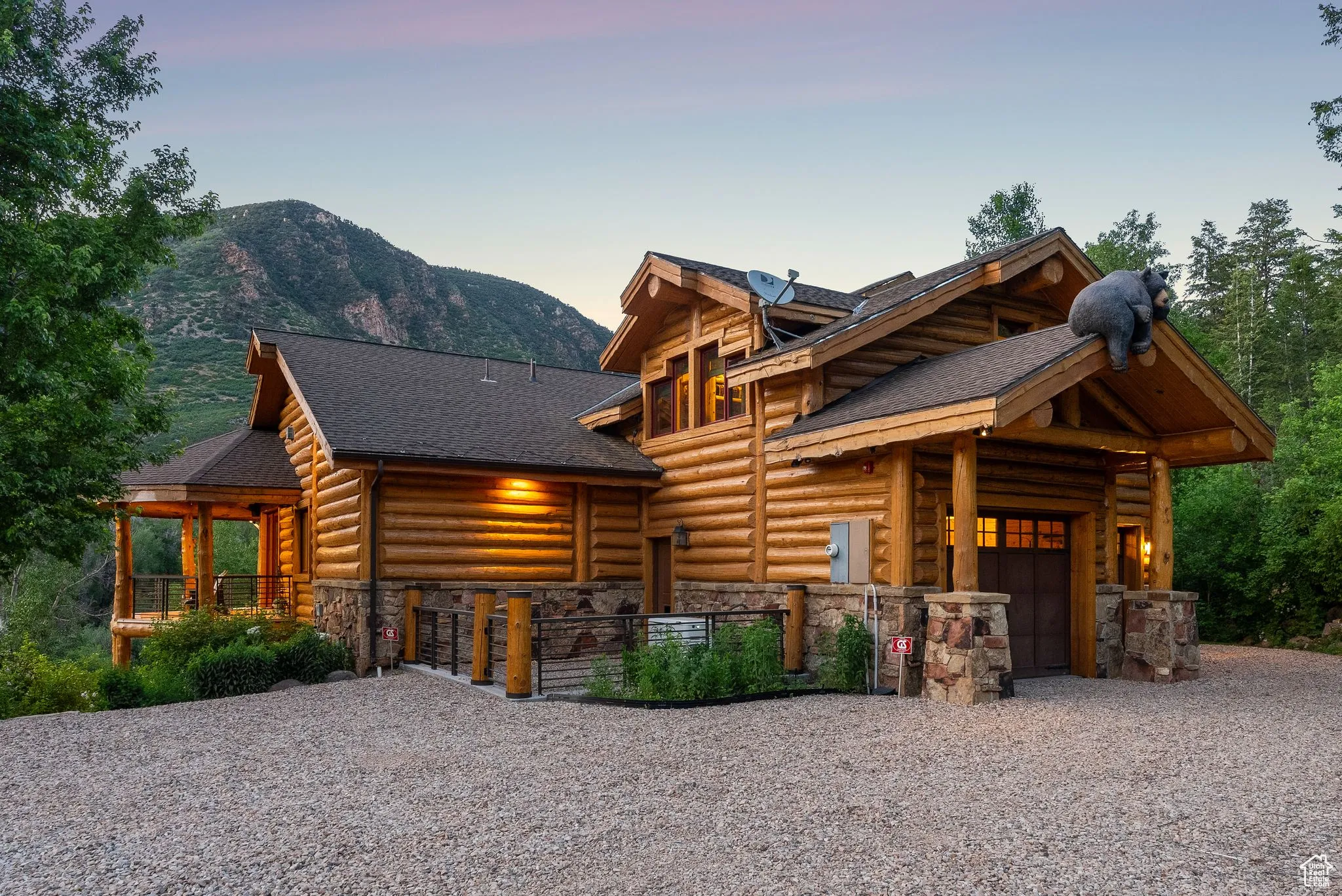 Split-log veneer, framed home featuring gravel driveway, stone siding, a garage, a mountain view, and a shingled roof