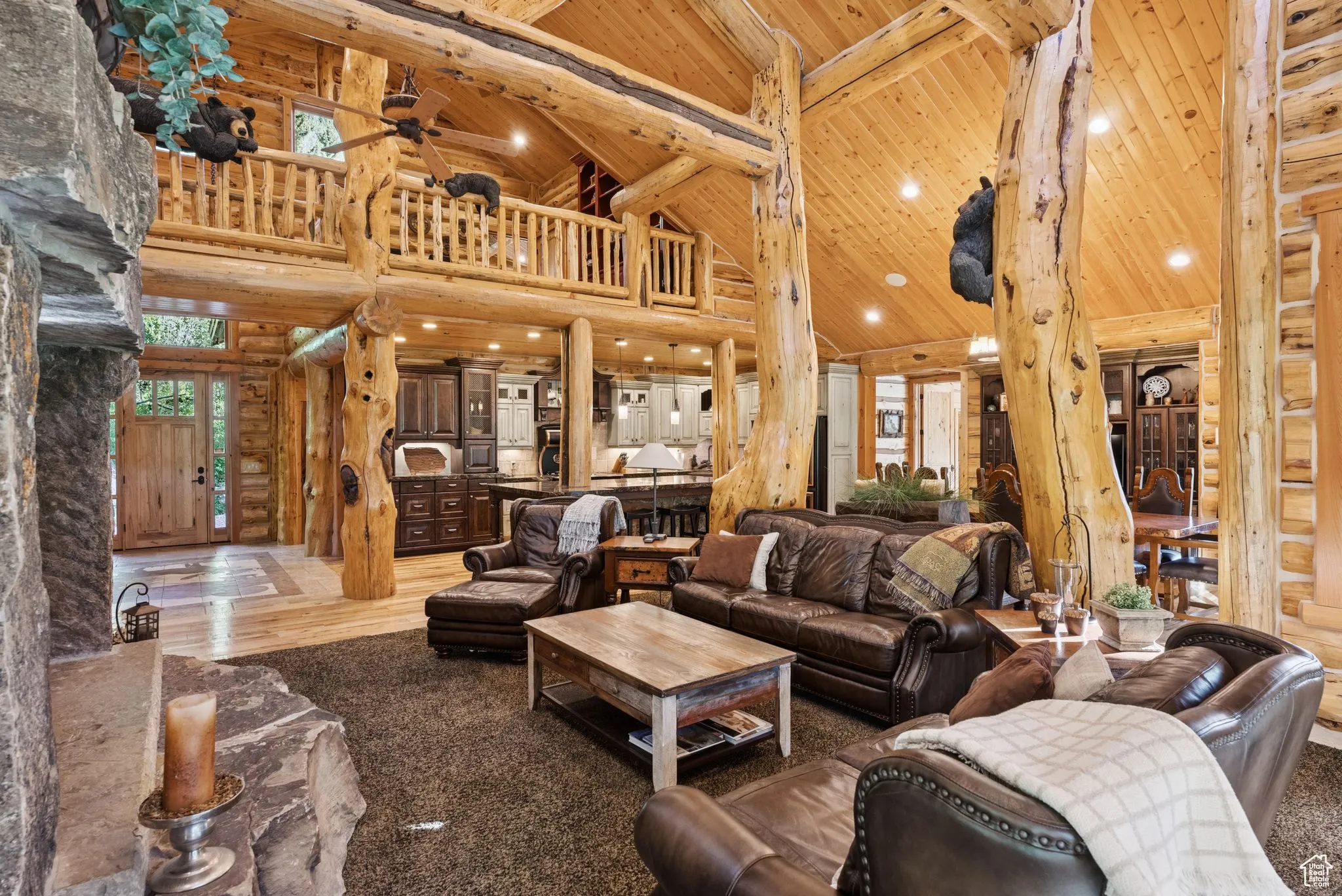 Living room with high vaulted ceiling, a tongue-in-groove ceiling with exposed beams, split-log walls, ceiling fan, and recessed lighting