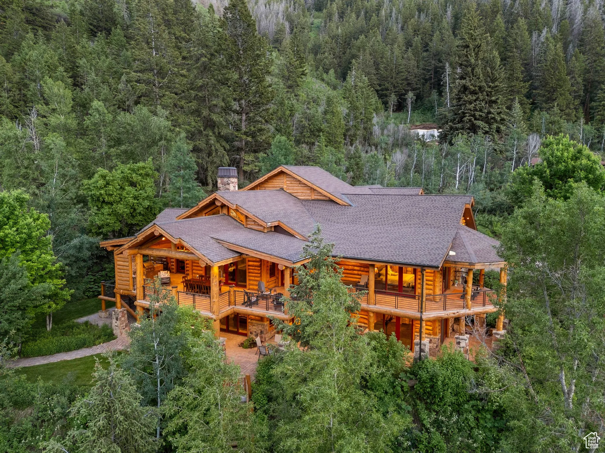 Rear view of house with split-log veneer, framed home exterior, a chimney, a wooded view, and roof with shingles