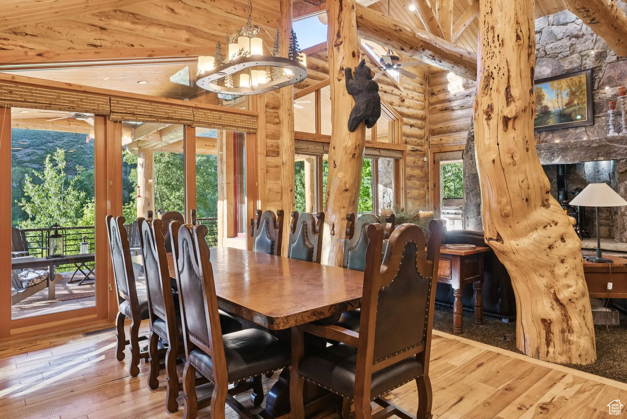 Dining area with high vaulted ceiling, hardwood flooring, rustic walls, a tongue-in-groove ceiling with exposed beams, and a chandelier