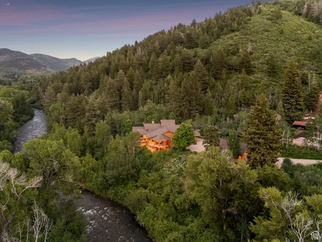 Aerial view of property and surrounding area featuring a heavily wooded area and mountains