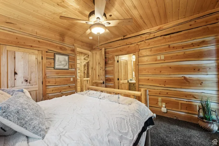 Carpeted bedroom with wood walls, tongue-in-groove ceiling, and ceiling fan