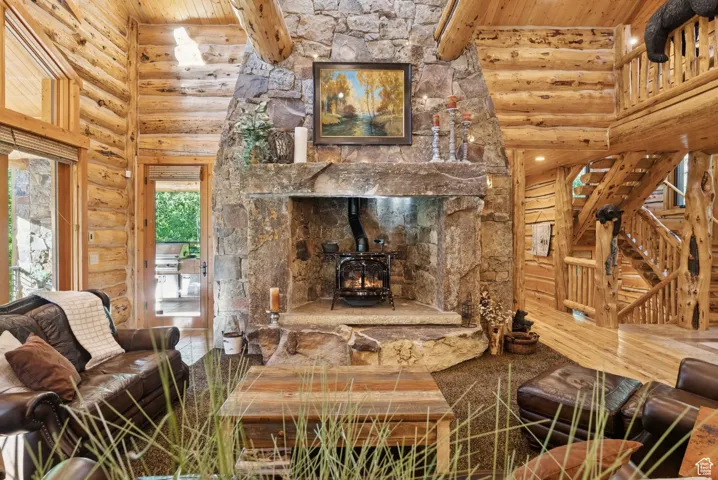 Living room with split-log walls, a wood stove, a tongue-in-groove ceiling with exposed beams, and a high ceiling