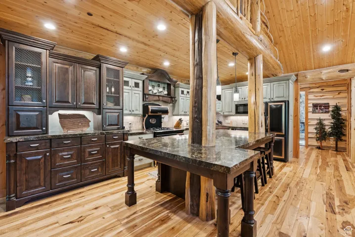 Kitchen with wooden ceiling, light wood finished floors, a kitchen bar, tasteful backsplash, and built in microwave