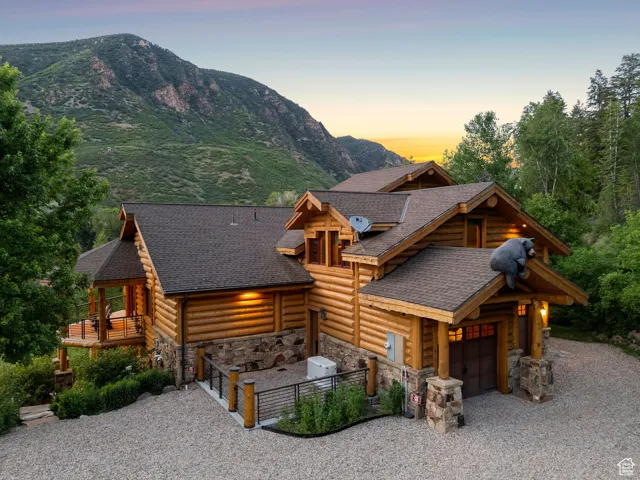 Split-log veneer, framed home with driveway, stone siding, a garage, a shingled roof, and a mountain view