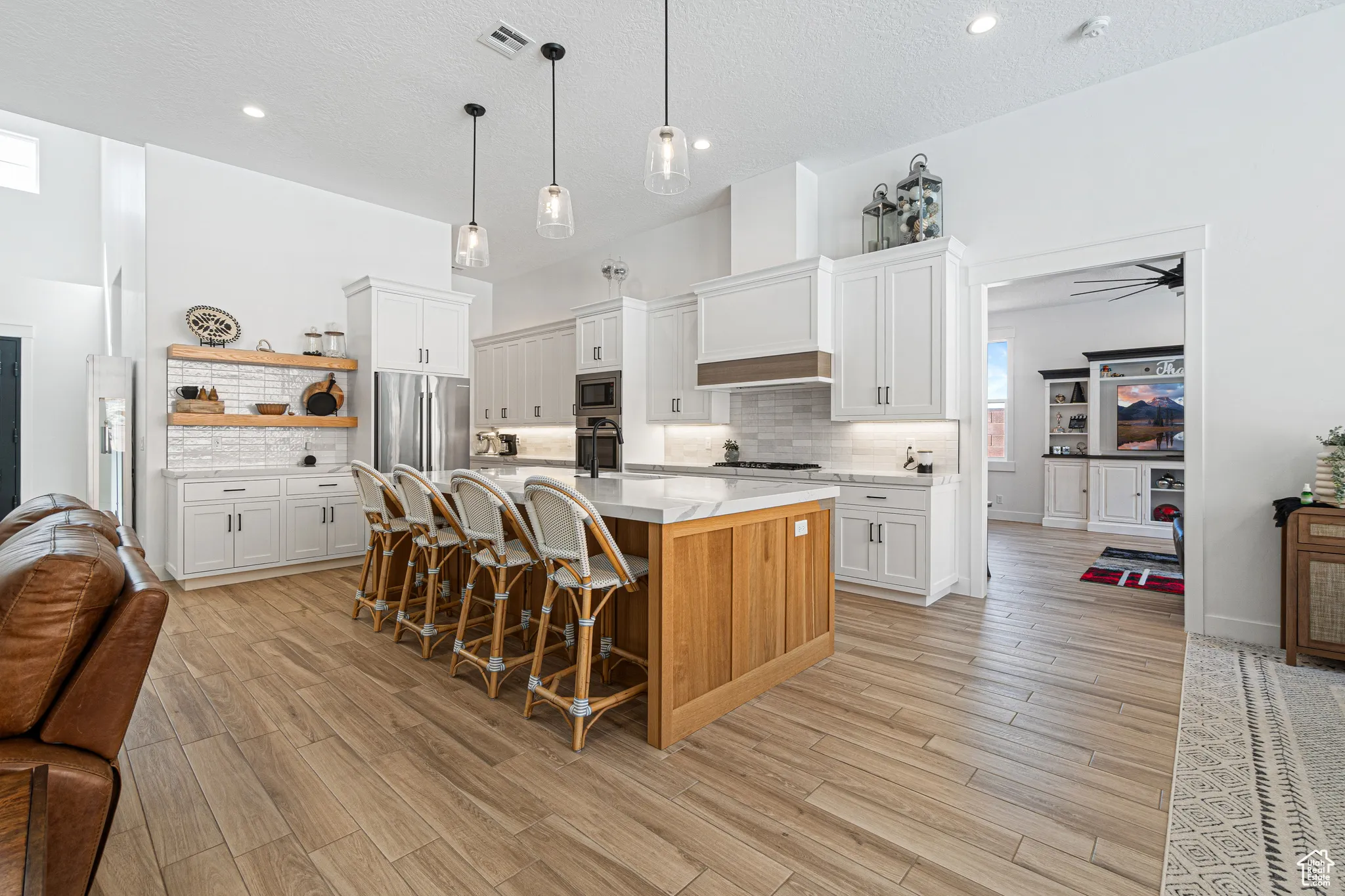 Kitchen with appliances with stainless steel finishes, open floor plan, light countertops, light wood finished floors, and recessed lighting