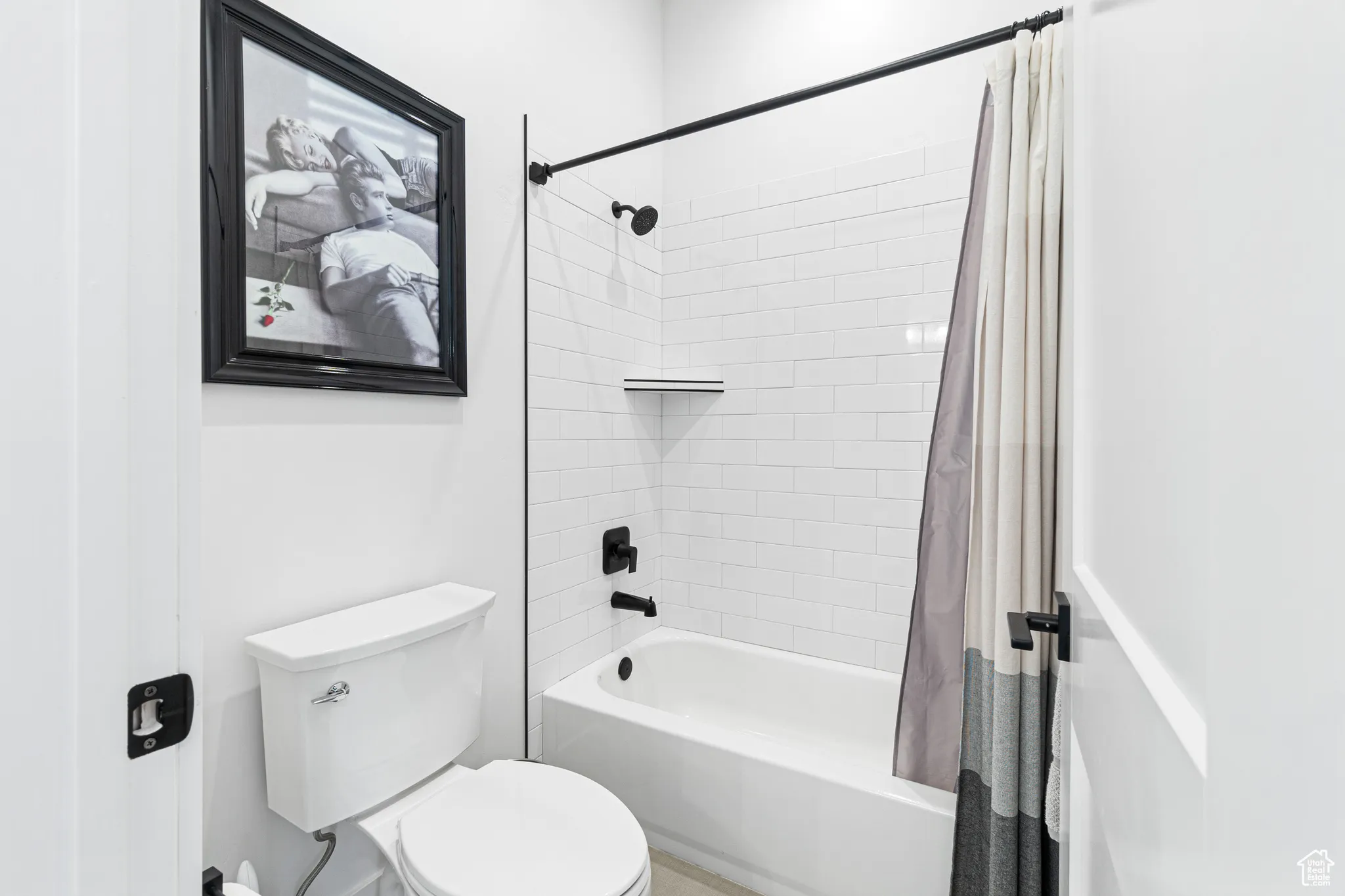 Bathroom with toilet and shower / bathtub combination with curtain