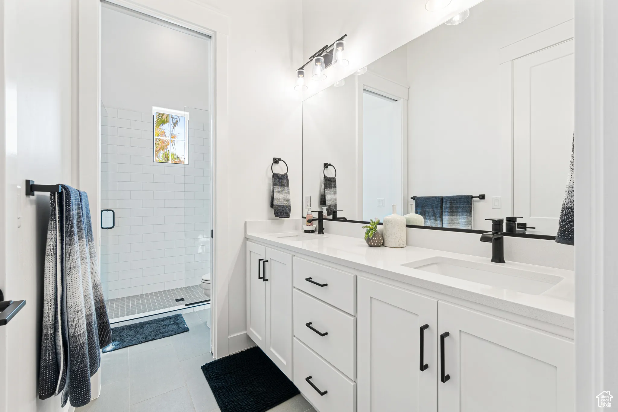 Bathroom with double vanity, a stall shower, and tile patterned flooring