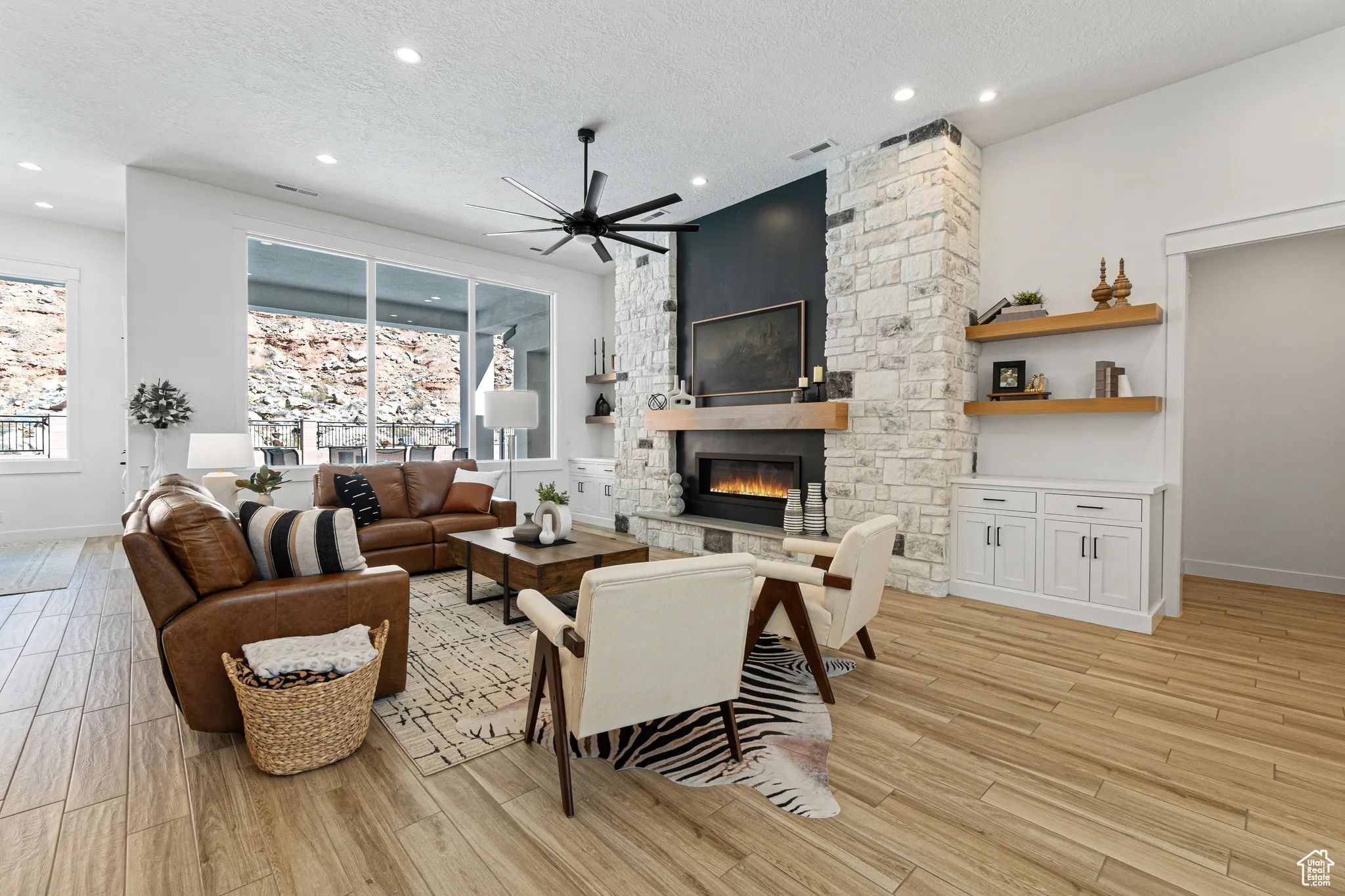 Living area with a fireplace, a ceiling fan, light wood-style floors, recessed lighting, and a textured ceiling