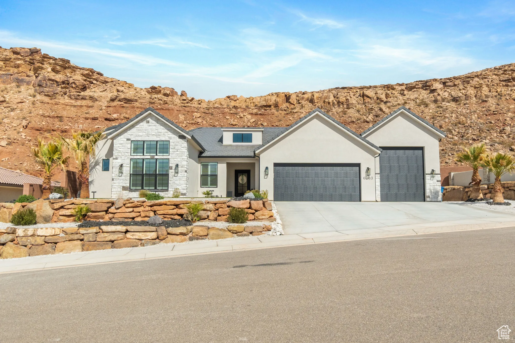 View of front of property with an attached garage, stucco siding, a mountain view, stone siding, and concrete driveway