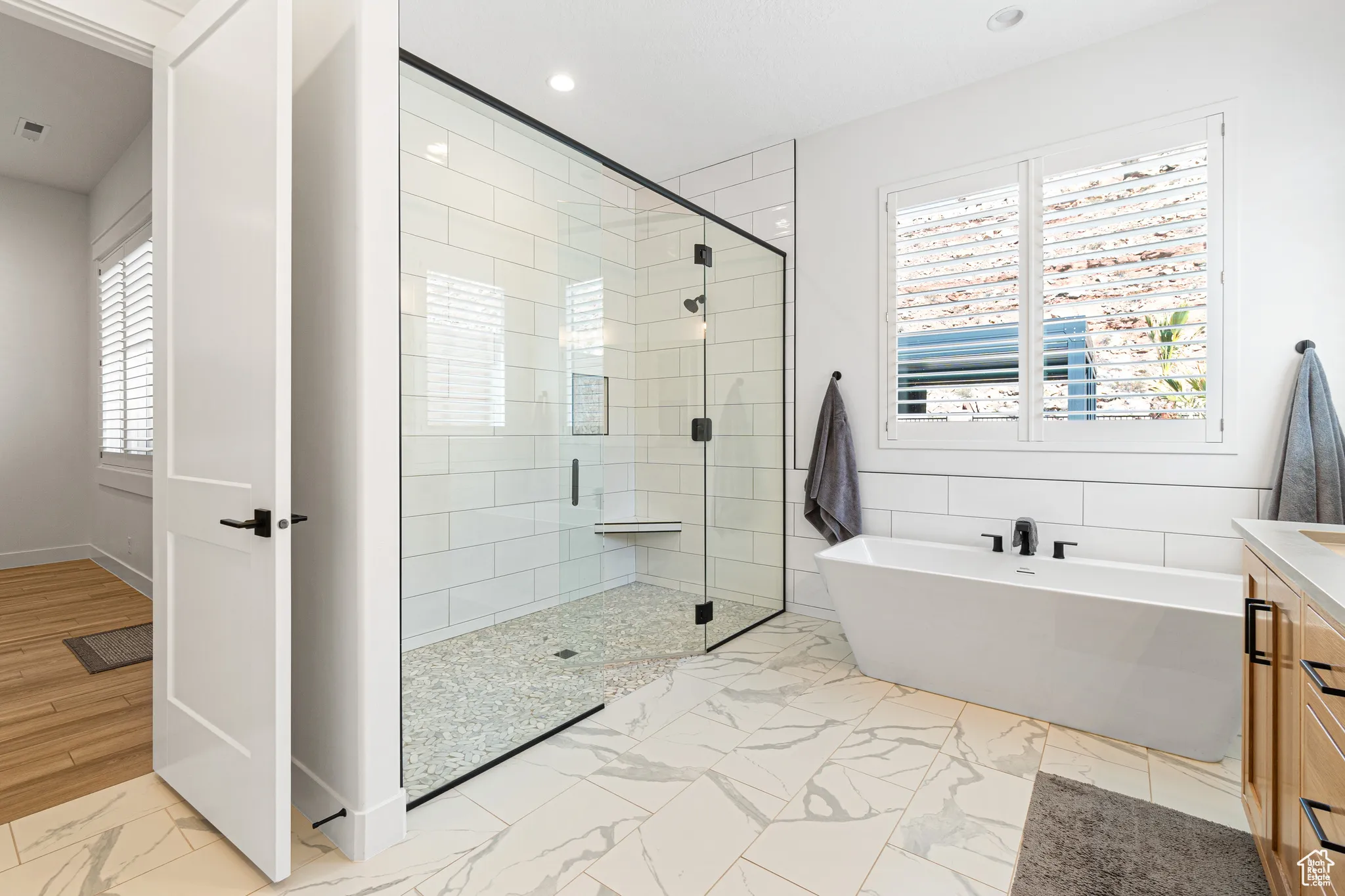 Bathroom featuring marble look tile flooring, a freestanding bath, a stall shower, recessed lighting, and vanity