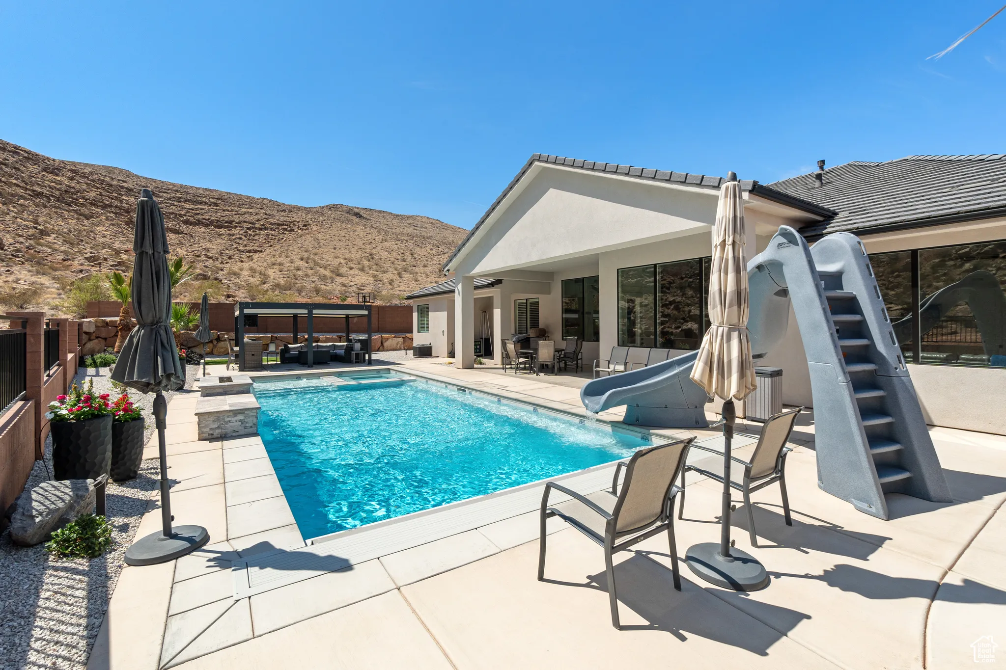 View of pool with a water slide, a mountain view, a jacuzzi, and a patio area