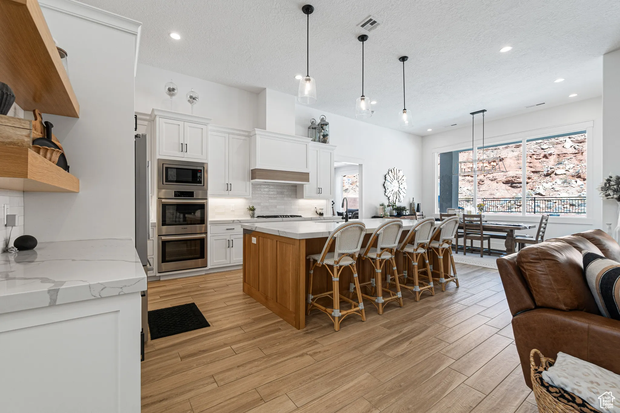 Kitchen with stainless steel appliances, open floor plan, decorative backsplash, light wood finished floors, and recessed lighting