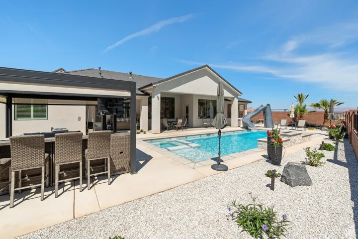 View of pool featuring a water slide, a patio, a fenced backyard, and a pool with connected hot tub