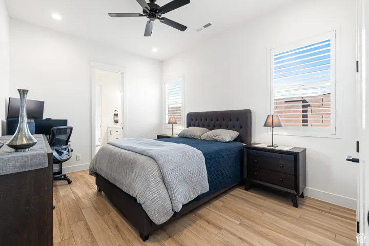 Bedroom with light wood-style floors, recessed lighting, a desk, connected bathroom, and ceiling fan