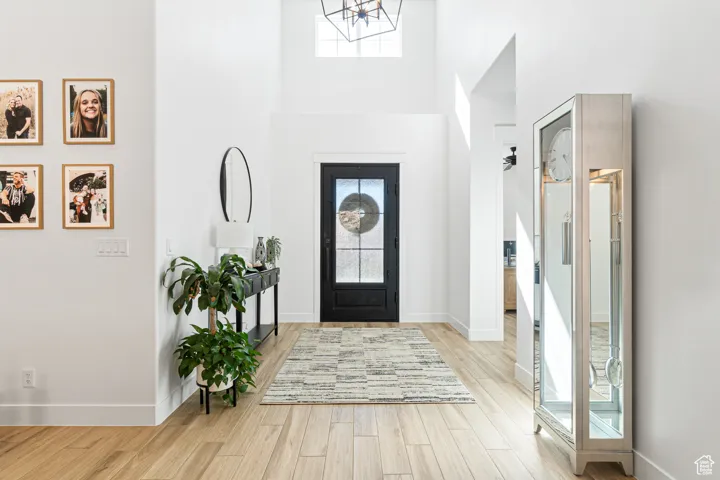 Foyer entrance featuring wood finished floors, a chandelier, and a high ceiling