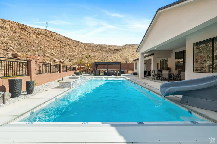 View of swimming pool featuring a water slide, a mountain view, an outdoor hangout area, a fenced backyard, and a patio