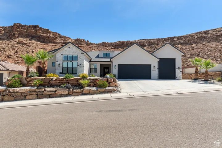 View of front facade featuring an attached garage, driveway, a mountain view, stone siding, and stucco siding
