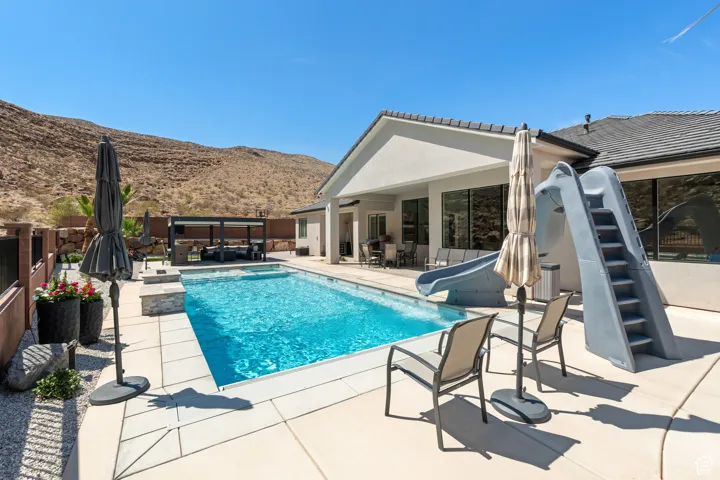 View of pool with a water slide, a mountain view, a jacuzzi, and a patio area