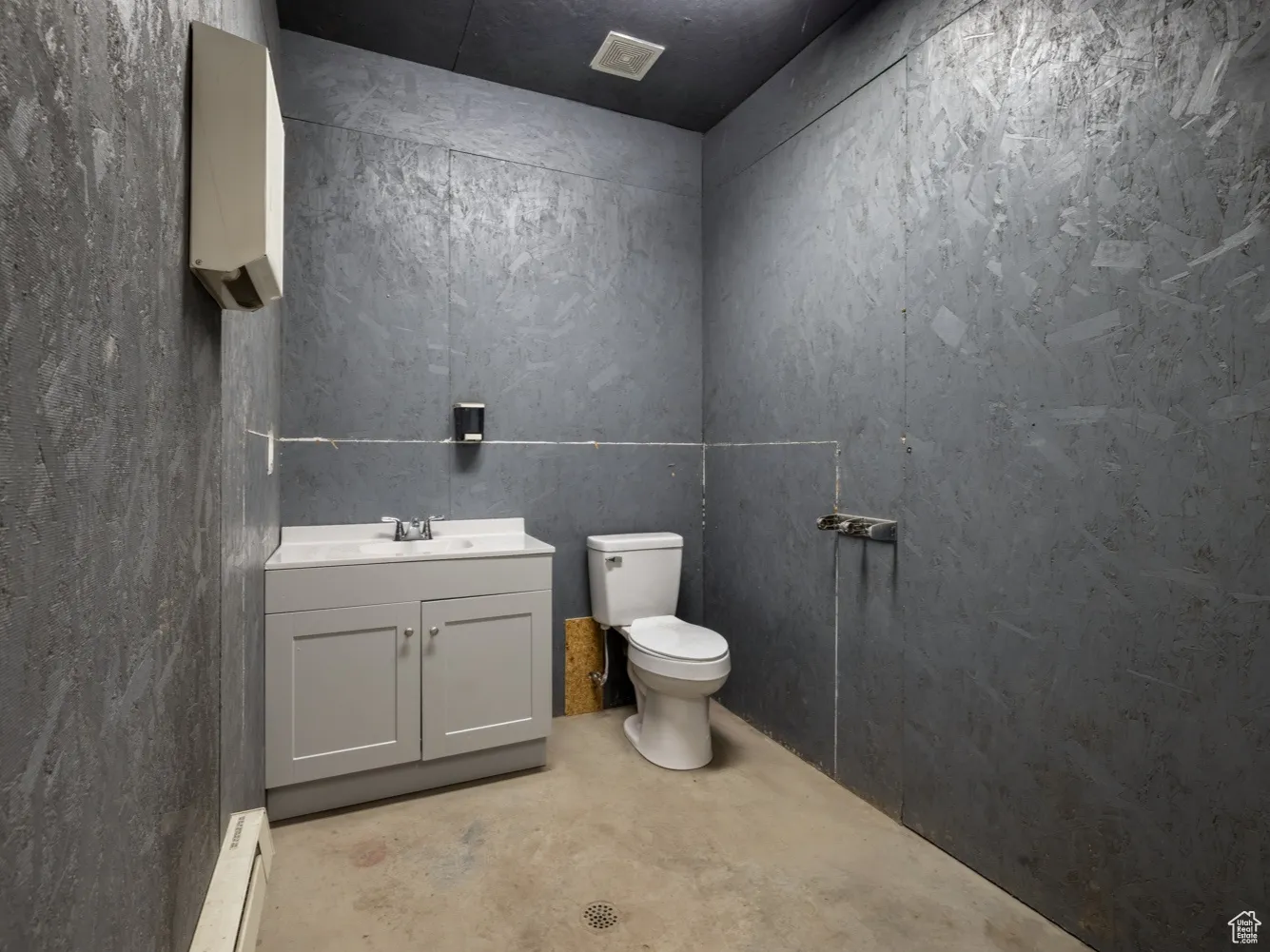 Bathroom with concrete flooring, vanity, and baseboard heating