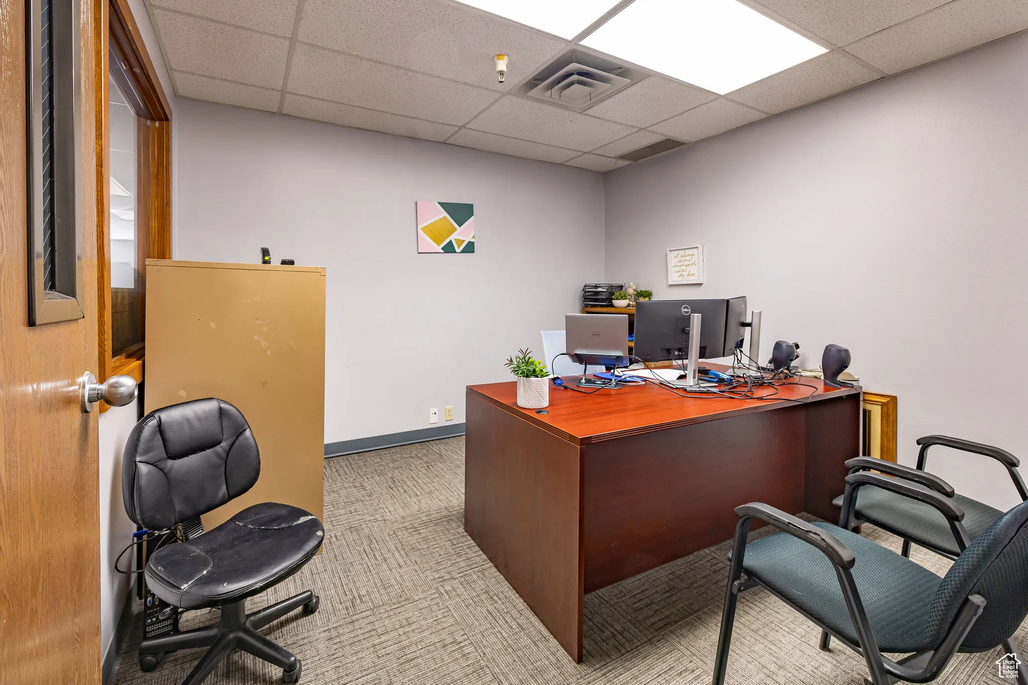 Office with carpet floors and a paneled ceiling