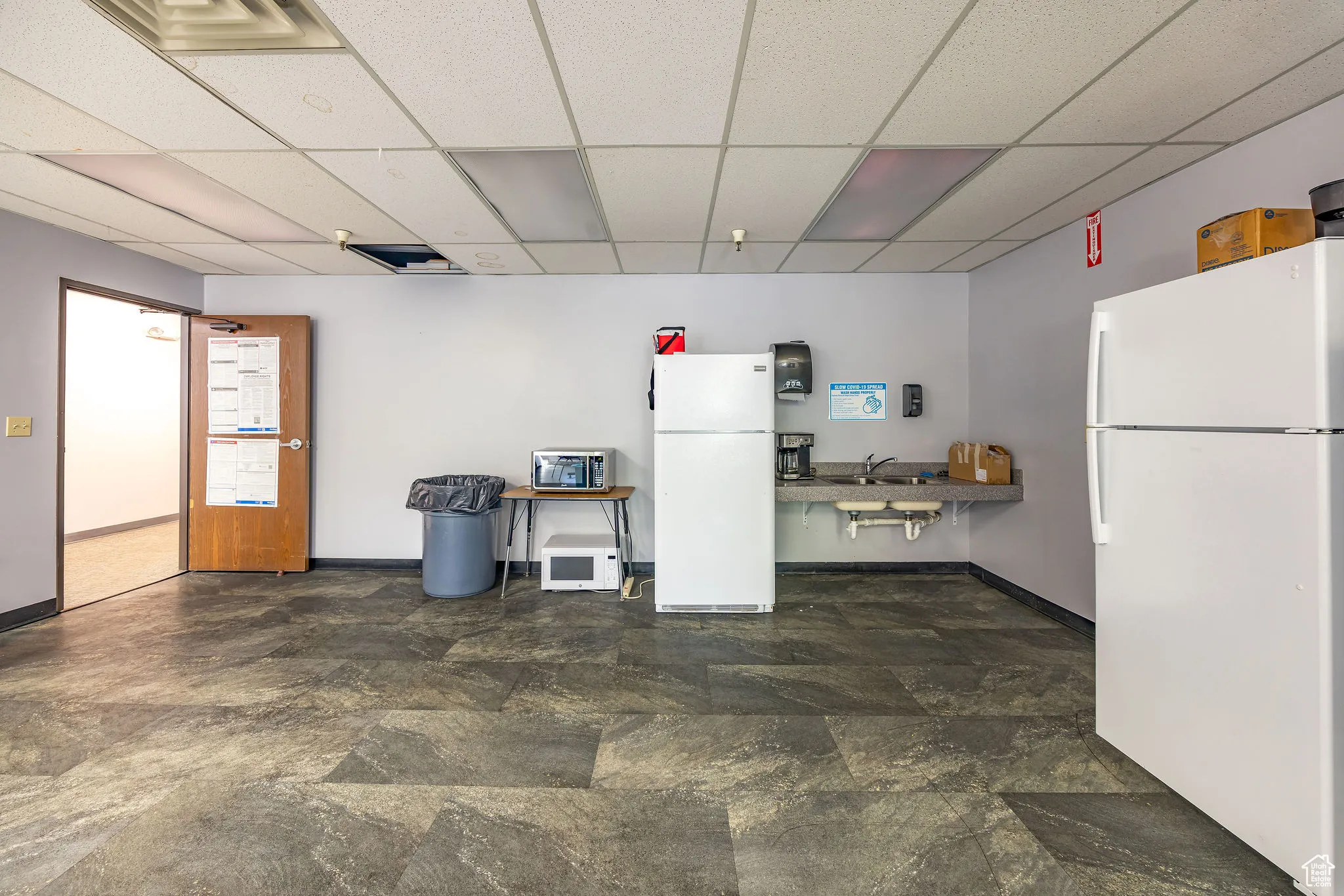 Kitchen featuring freestanding refrigerator, a drop ceiling, and stone finish floors
