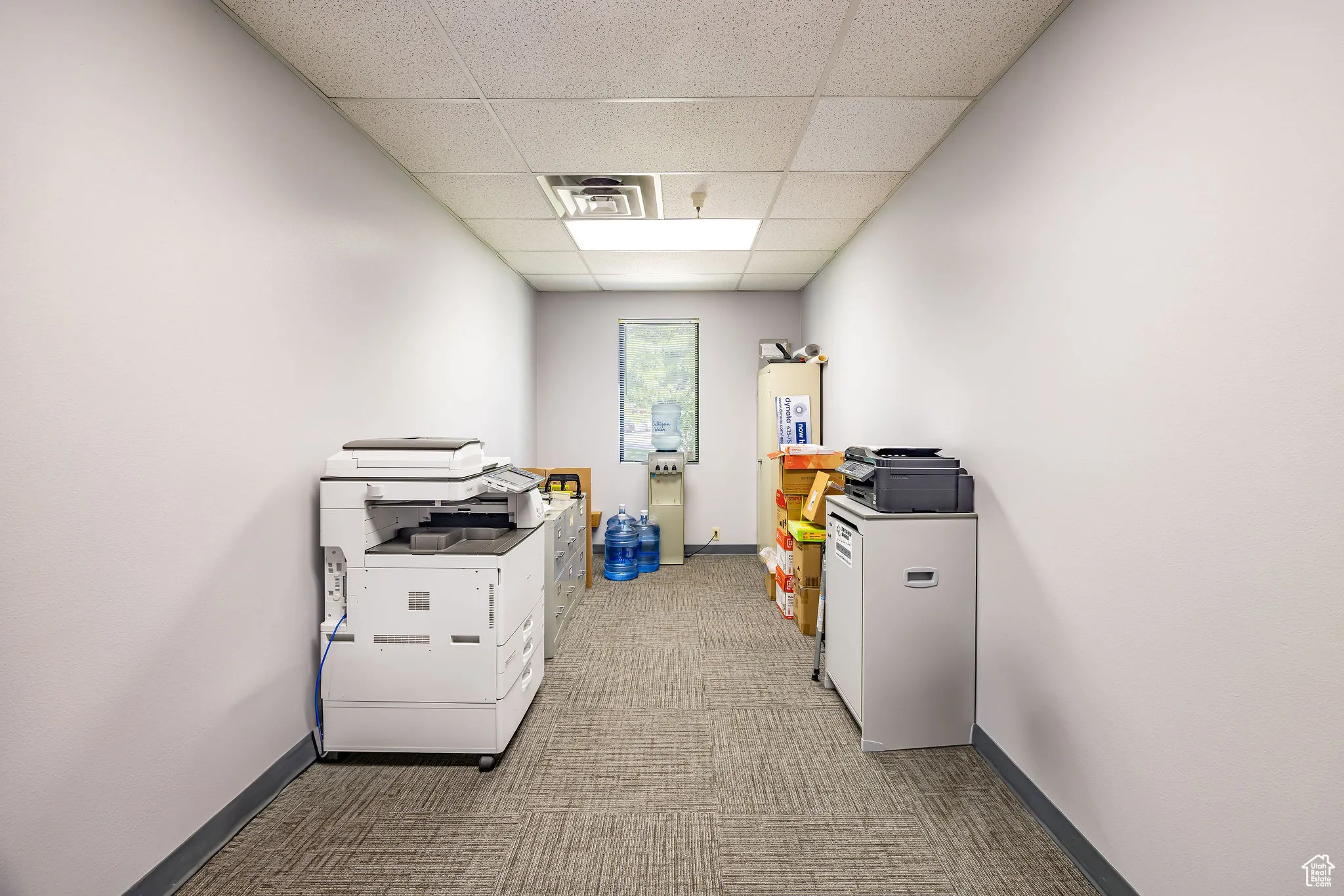 Office area with a drop ceiling and carpet flooring