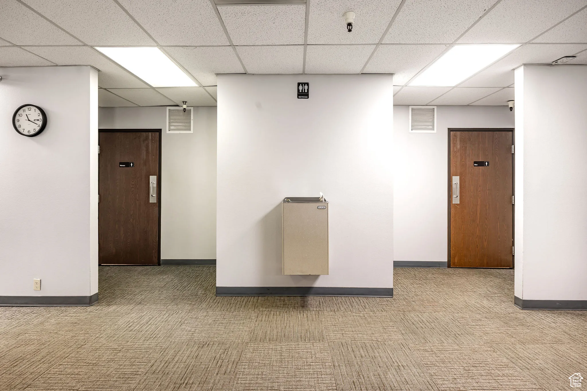 Corridor with a paneled ceiling and carpet flooring