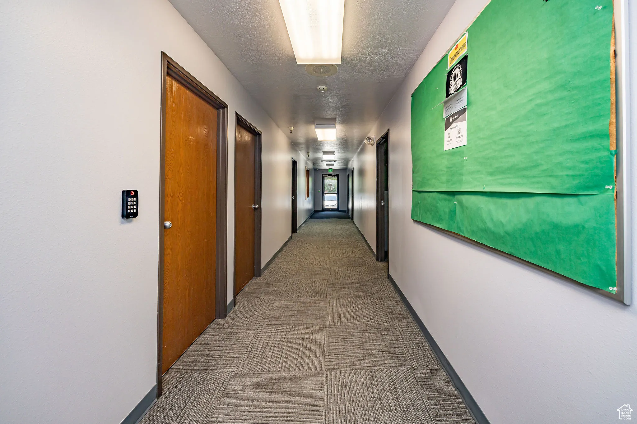 Corridor featuring carpet floors and a textured ceiling