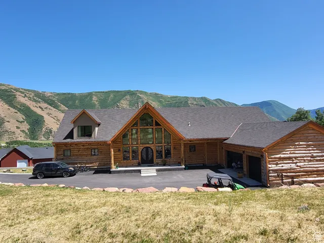 Back of house with a mountain view, an attached garage, and a yard