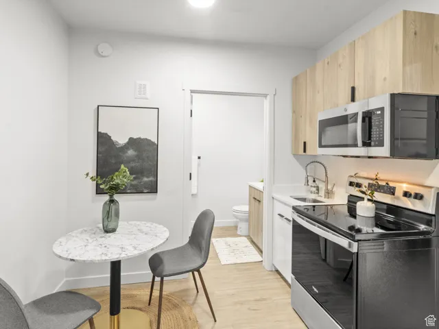Kitchen featuring appliances with stainless steel finishes, light brown cabinetry, light wood-style flooring, and light countertops