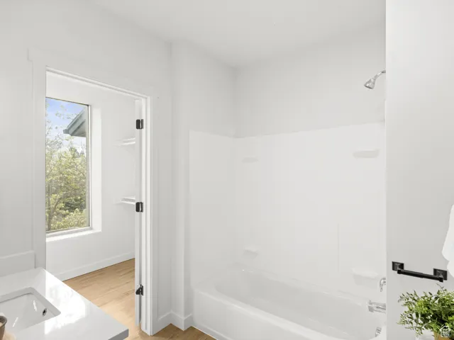 Full bath featuring bathing tub / shower combination, wood finished floors, and vanity