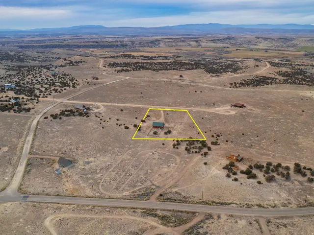 Aerial view of sparsely populated area featuring a mountain backdrop and property parcel outlined